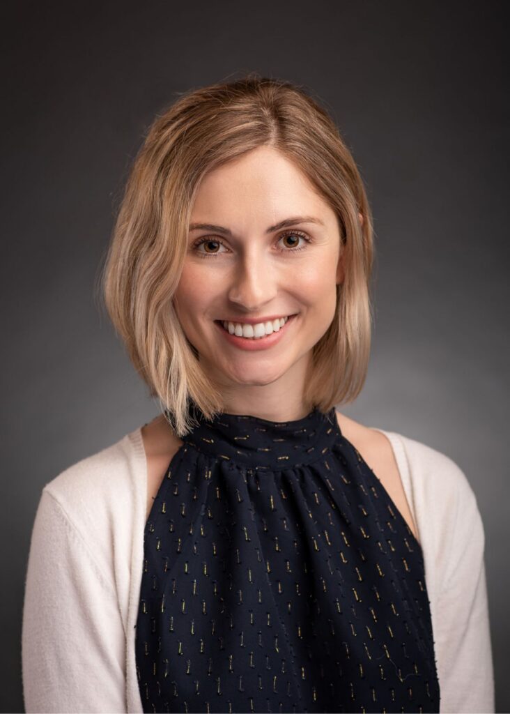 Headshot of a woman with blonde hair wearing a blue top, smiling softly at the camera.